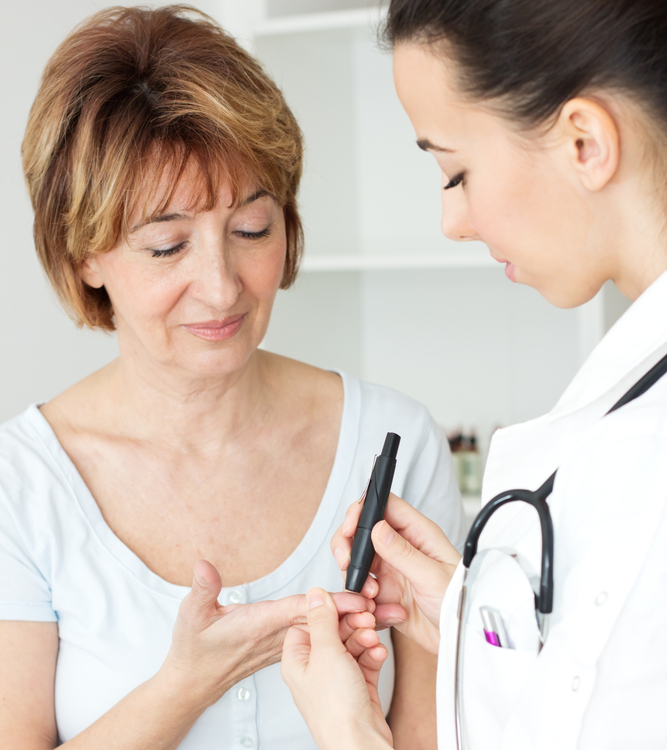 Image of a woman having blood drawn from her fingertip by a female doctor